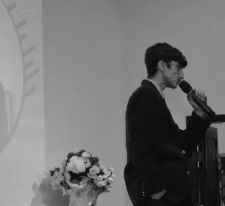 Munim khan giving a speech and holding mic in left hand